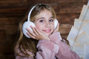 Niña con orejeras de nieve haciendo una cara preciosa en sesión de fotos de Navidad
