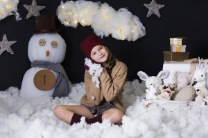 Niña sonriente entre nubes de algodón en una sesión infantil de Navidad en Valencia con Mar Atienza Fotografía.