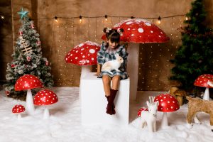 niña con coneja sobre las piernas en escenario navideño con setas rojas