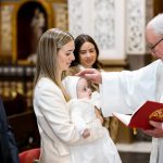 Sacerdote derramando agua en bautizo en Valencia.