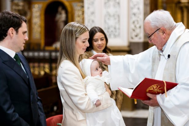Sacerdote derramando agua en bautizo en Valencia.