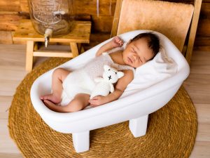 Fotografía de recién nacido en bañera con fondo de madera y decoración cálida