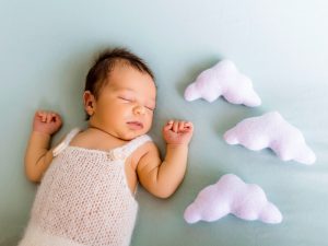 Bebé dormido con decoración de nubes en sesión de fotos newborn Título: Un sueño de ternura