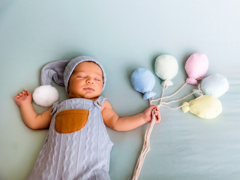 ¿Qué precio tiene una sesión de fotos de recién nacido y qué incluye? Bebé recién nacido con globos pastel en una sesión de fotos creativa y profesional