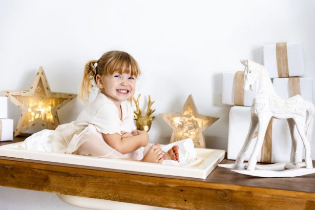 Niña jugando junto a un caballo de madera en una sesión de Navidad en Valencia