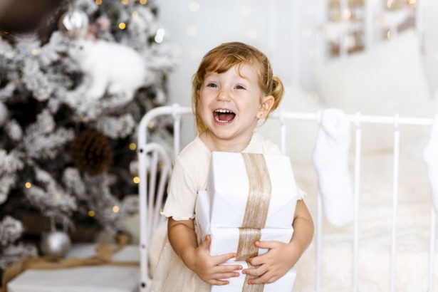 Niña sonriendo con tres regalos blancos durante una sesión de Navidad en Valencia