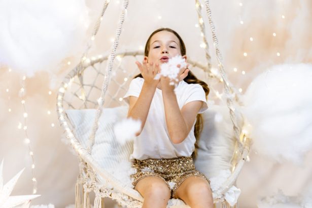 Niña soplando nieve desde un columpio durante una sesión de Navidad en Valencia