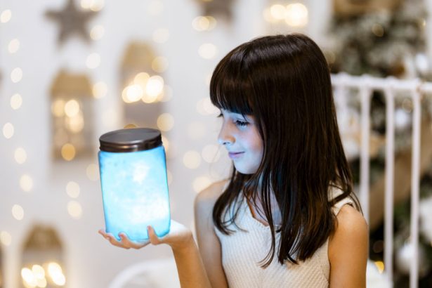 Niña sosteniendo un tarro luminoso durante una sesión de Navidad en Valencia