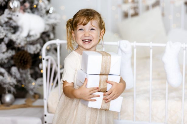 Niña pequeña riendo con regalos durante una sesión de fotos de Navidad en Valencia