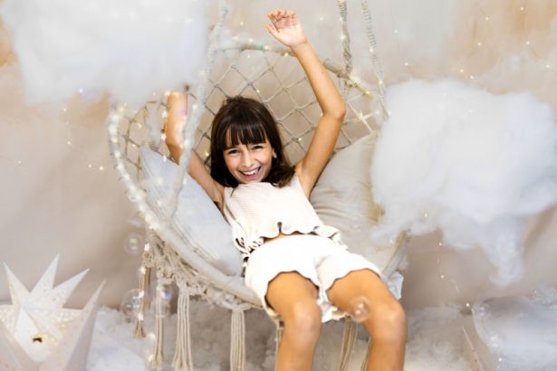 Niña riendo en un columpio entre nubes durante una sesión de Navidad en Valencia